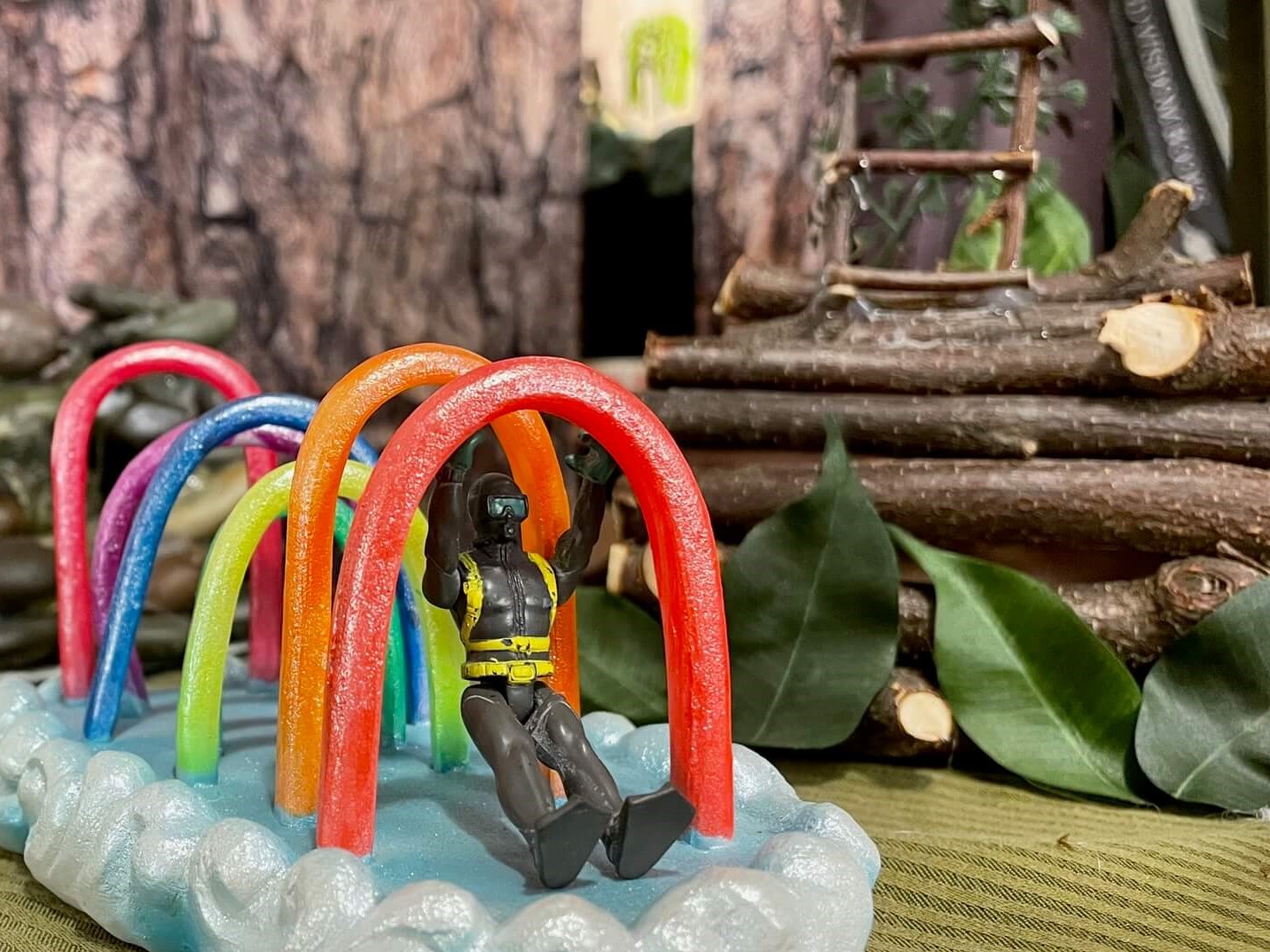 Toy swinging on rainbow archways on a cloud, in front of a treehouse ladder made of twigs.